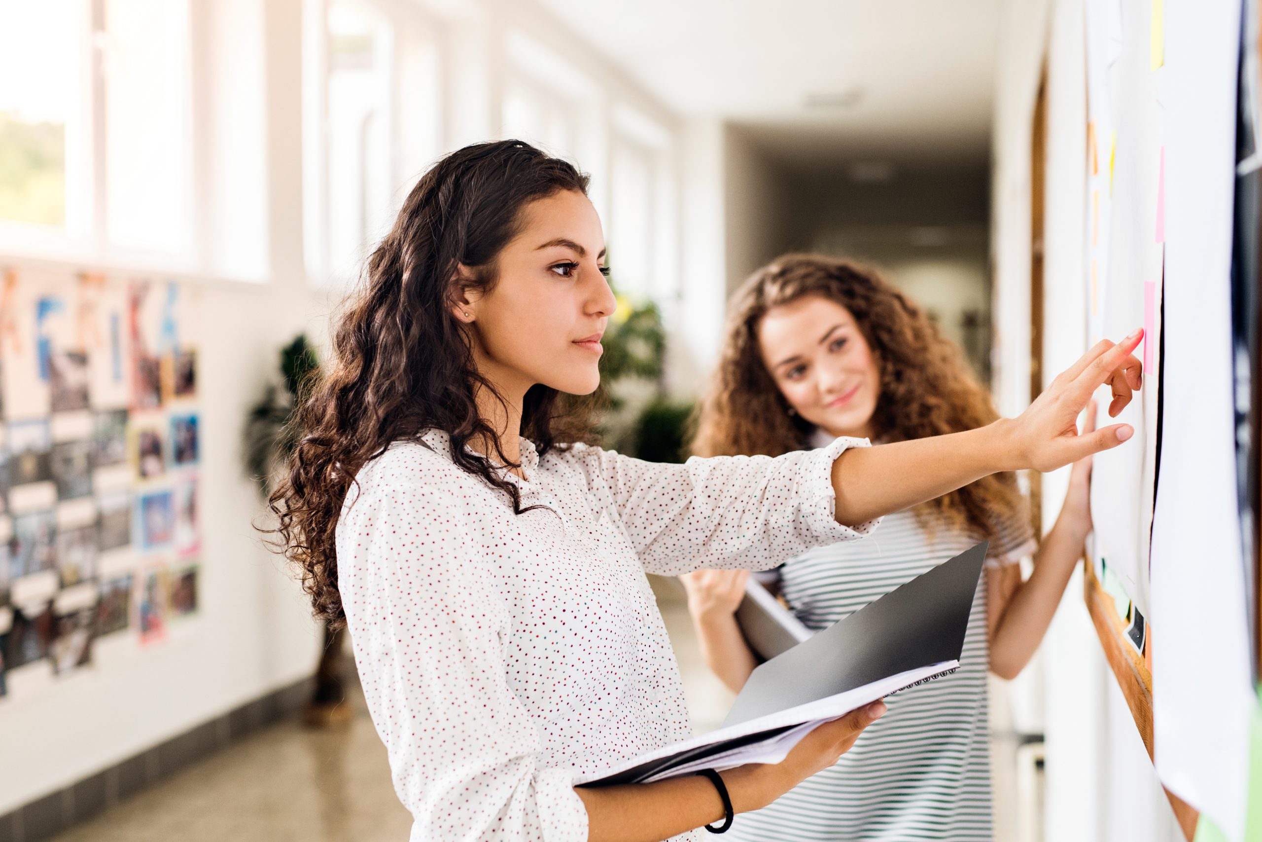 Reglement intérieur d'INEAD, école en ligne. Jeune fille consultant un reglement sur un panneau d'affichage.